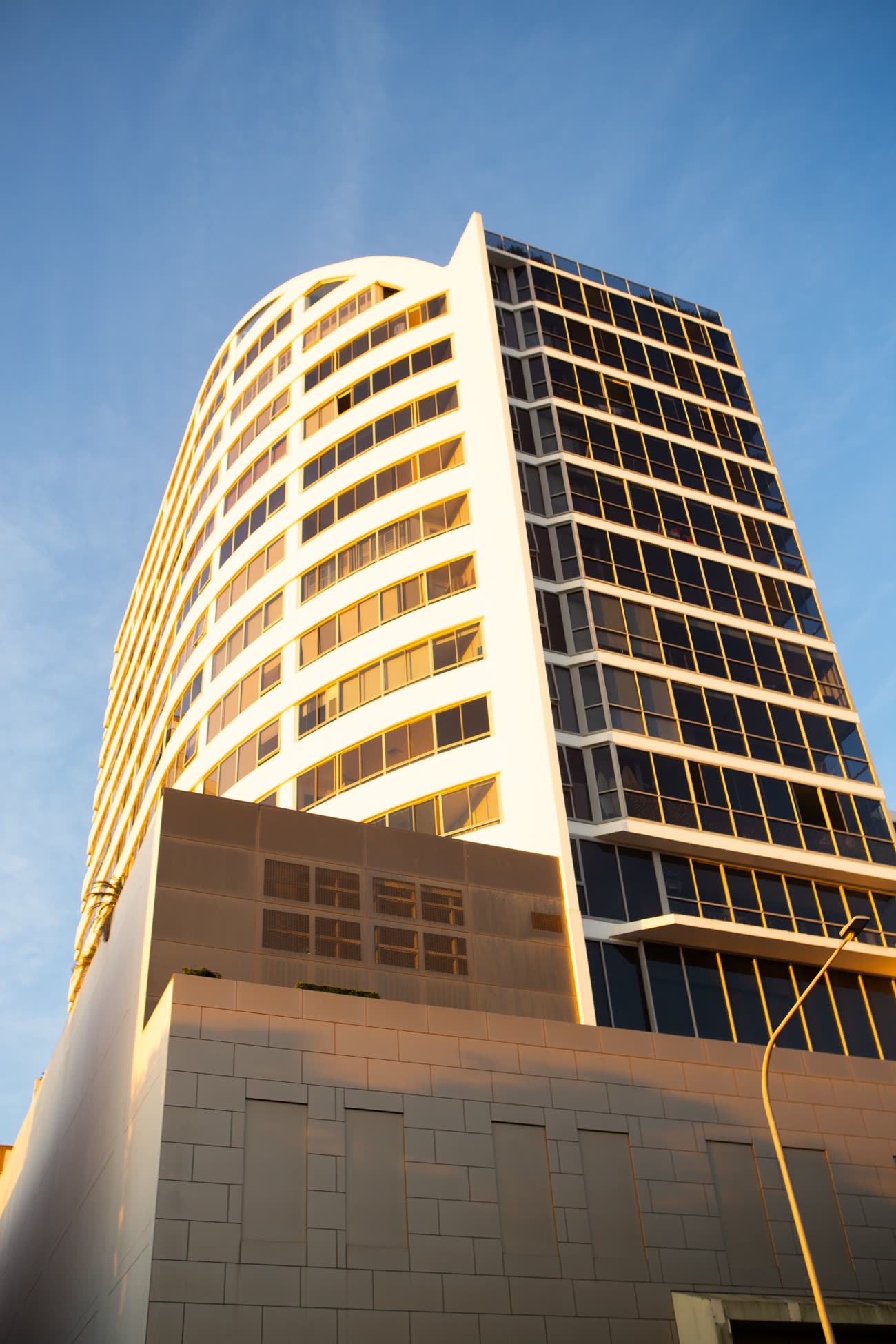 Curved residential tower in Sydney catching low golden hour light on its facade